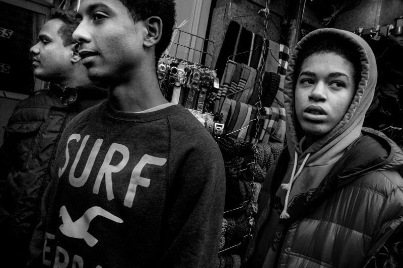Black and white close photo of two young men in a crowd, one in a SURF sweatshirt, both looking off to the side