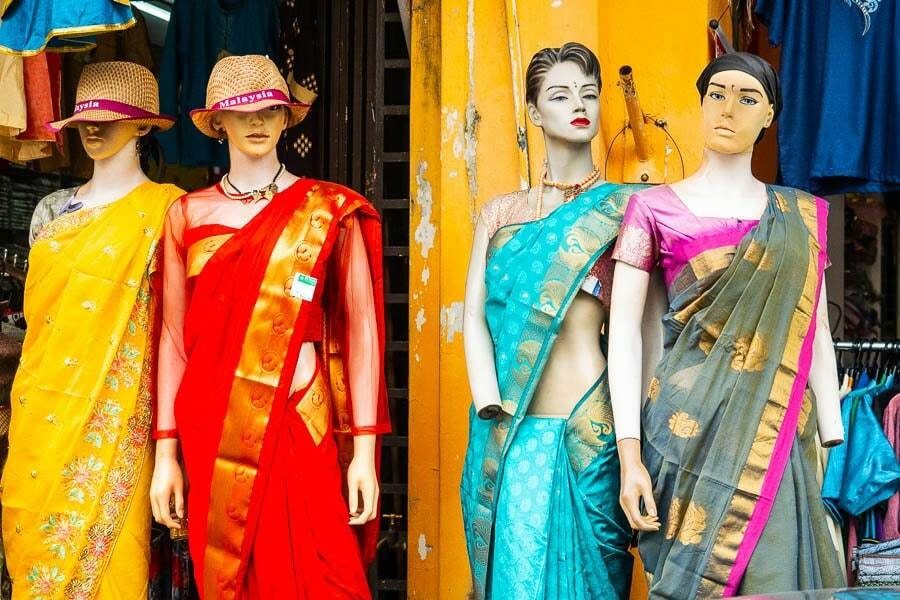 Row of mannequins in a shop front wearing bright saris in yellow, red, turquoise and green