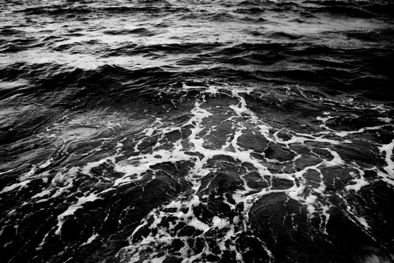 Grainy high contrast black and white close up of sea waves breaking