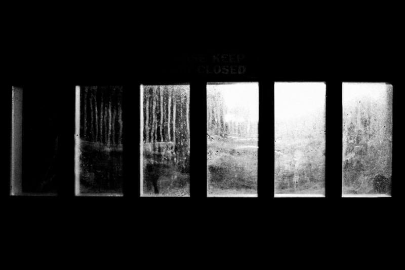 Five backlit window panes in a dark wall, black and white photograph