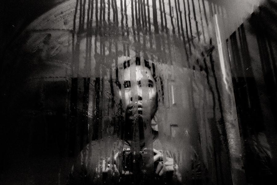 A woman's face seen through a wet, streaked window in black and white