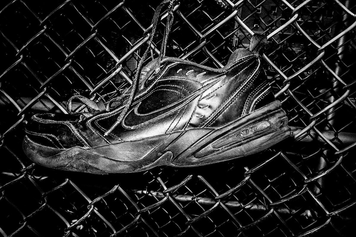 An old sneaker caught in a chain link fence, high contrast black and white