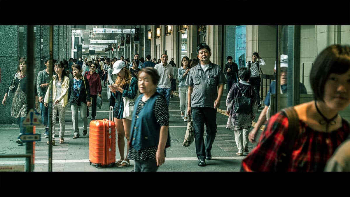 Crowd of pedestrians walking down a busy street in Japan, in a wide cinematic crop