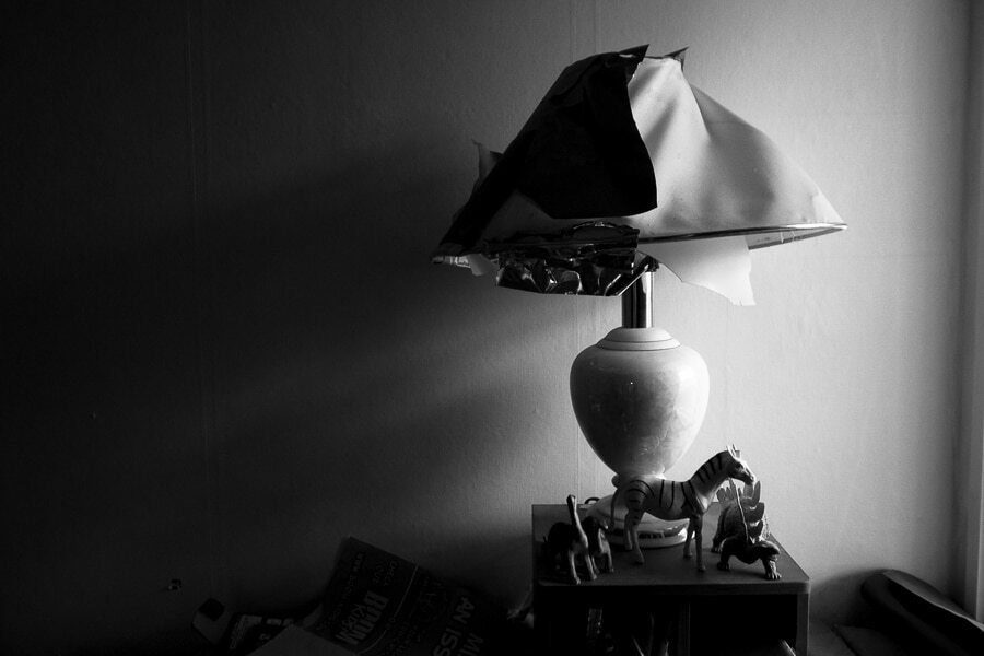 Black and white photo of a table lamp with a crumpled shade in soft window light at home