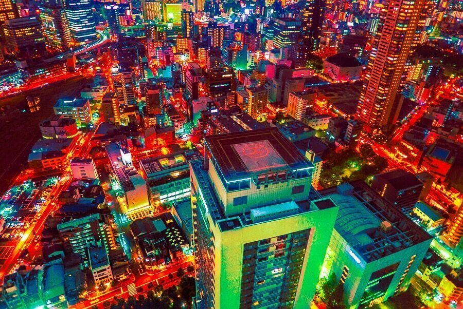 Colour night view looking down on a Japanese city with red, green and yellow lit buildings