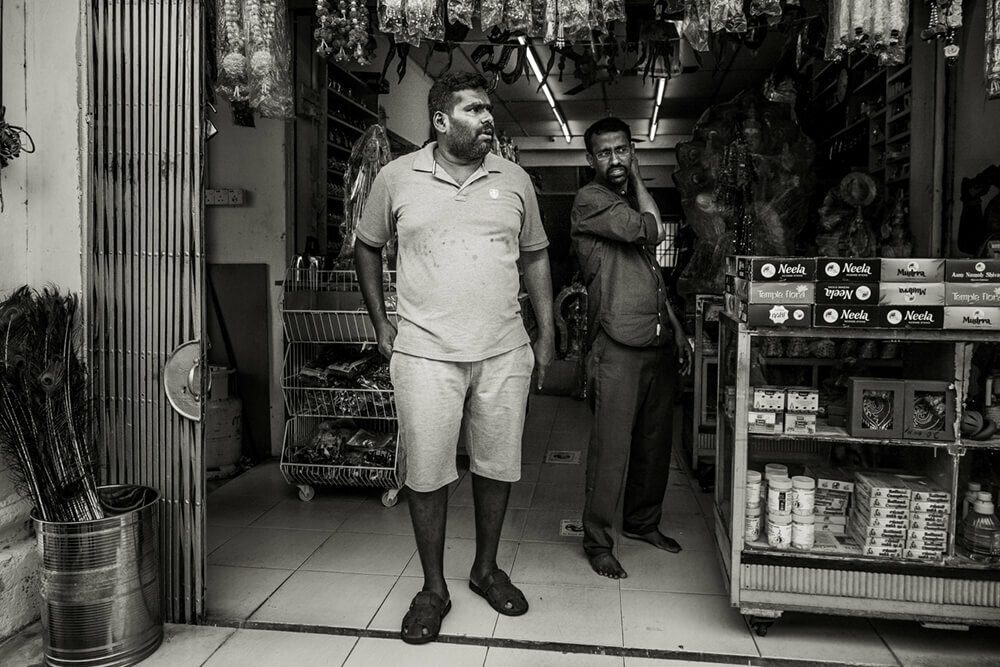 Black and white photo of two men standing in the doorway of a shop in Penang