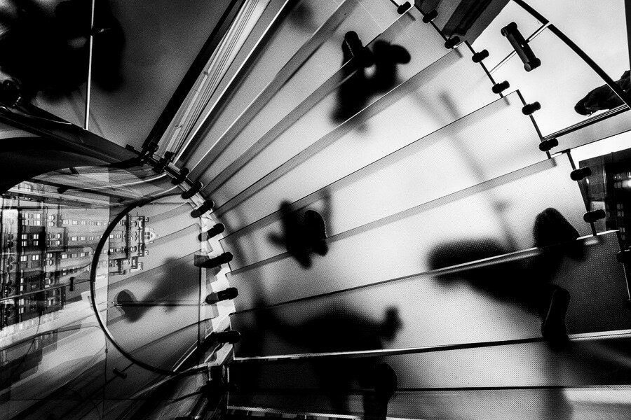 Black and white street photo of hard shadows falling across curved metal shutters