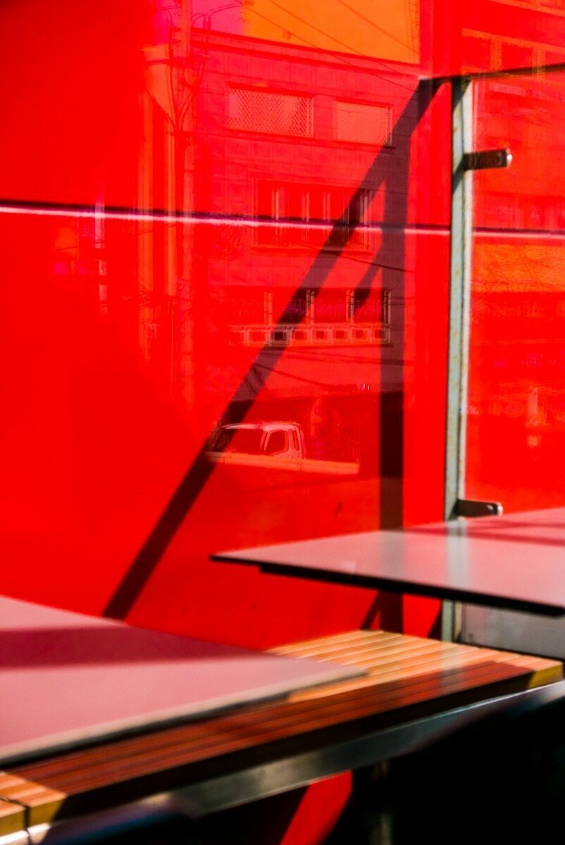 Vertical photo of a bright red glass wall with a metal railing and a table edge in front of it