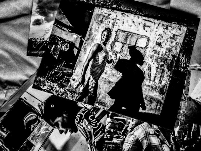 Black and white test prints of street photographs spread on a table