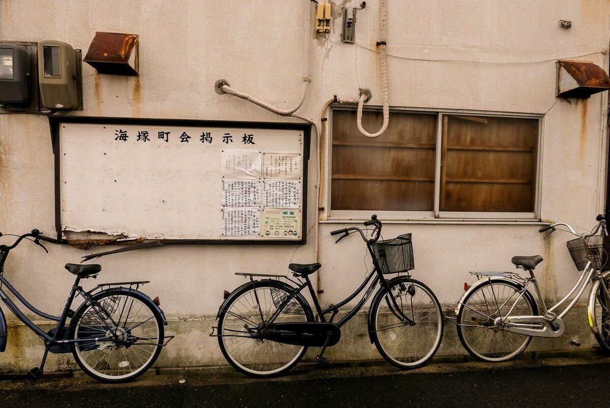 Three bicycles parked against a weathered wall below a window