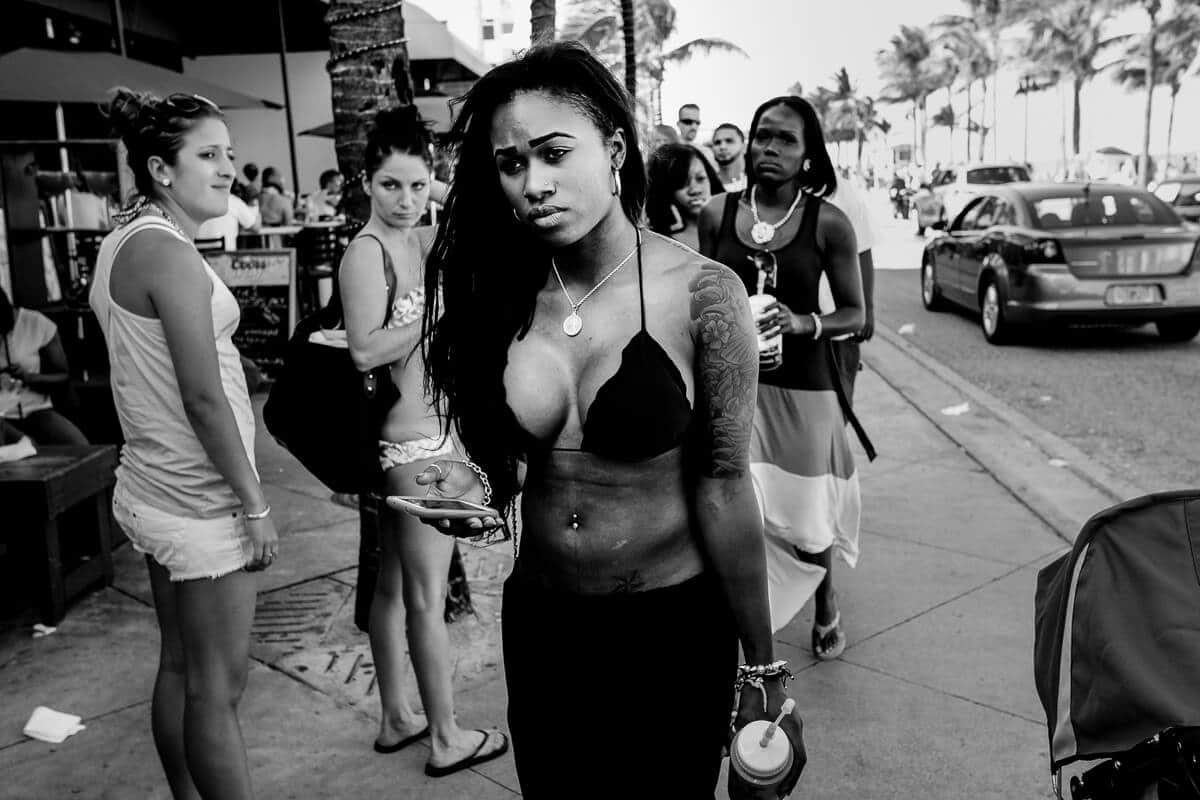 Black and white photo of young women walking on a sunny Miami sidewalk with palm trees and hard shadows