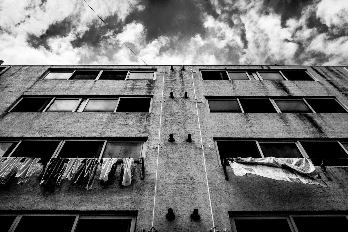 Low angle of an apartment block with laundry hanging from the balconies under a dramatic sky