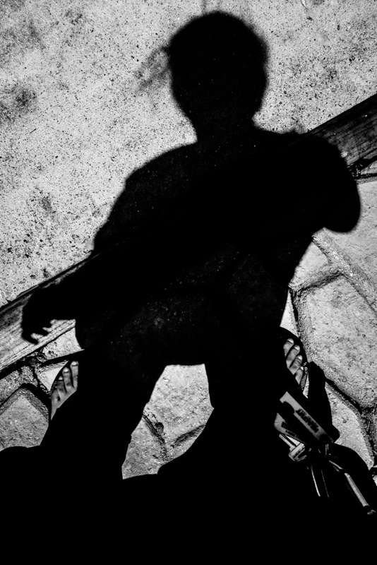 Black and white shadow self-portrait of a photographer cast on rough pavement