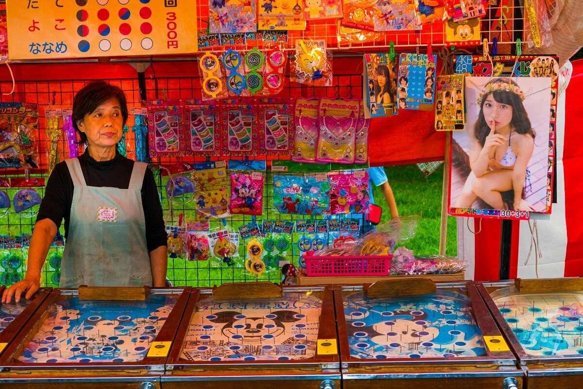 A woman behind a colorful game stall at a fair