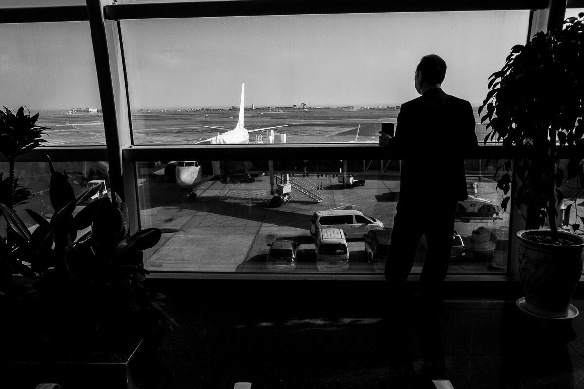 Silhouette of a man looking out an airport window at the runway