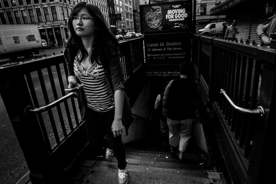 Woman walking up the stairs of Canal St subway station in New York, black and white street photo